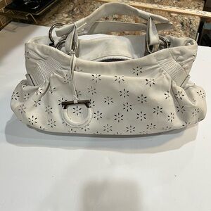 Top handle white leather Ferragamo bag with laser floral cutout details.